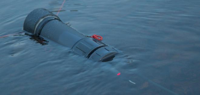 A logger, consisting of a microcontroller, a battery, an SD card, and a temperature sensor, recording from 16 electrodes placed on the riverbed. A status LED indicates that it is recording.